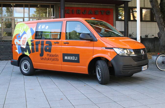 Kirja-auto Mirja on oranssi pakettiauto, jonka kyljessä on sen logo.